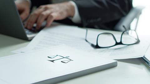 Justice scales on a file next to a laptop