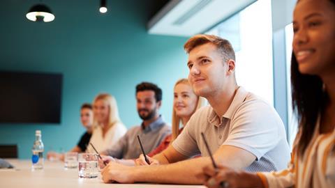 Solicitor apprentices take notes in an office meeting