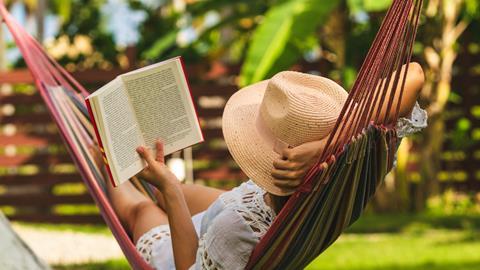 Woman lounges in hammock while reading on holiday