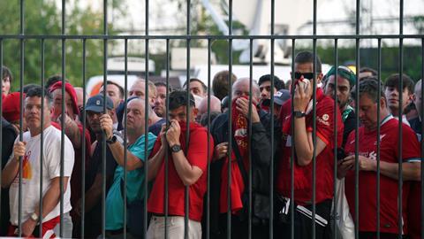 Liverpool fans cover their mouths and noses as they queue to gain entry to the Stade de France, Paris, ahead of the 2022 UEFA Champions League Final