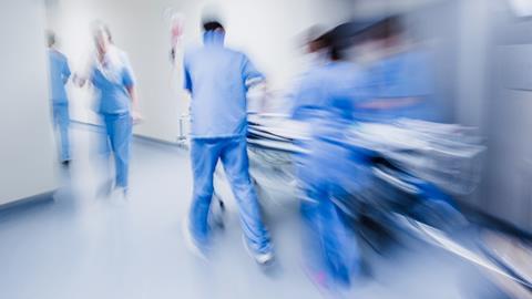 Blurred figures of hospital staff in scrubs rushing patient to surgery