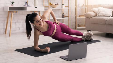 A young woman does an online pilates class