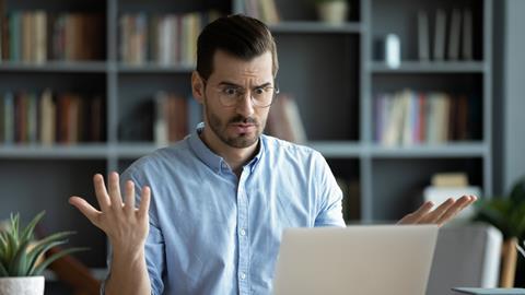 A man looks perplexed as he works on his laptop