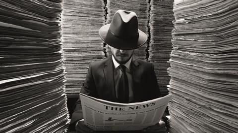 Reporter reading a newspaper surrounded by piles of news