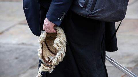 A barrister holds his wig on his way to court