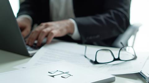 Justice scales on a file next to a laptop