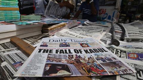 People read front page news of Taliban taking over Kabul, at a newspaper stall in Karachi, Pakistan