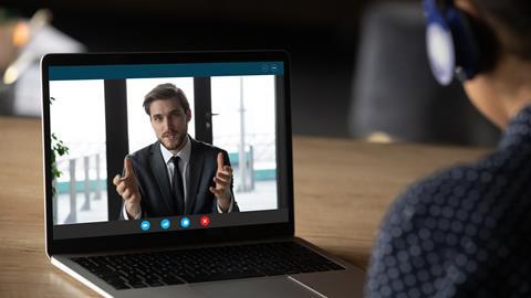 Laptop screen shows businessman talking to woman via Skype