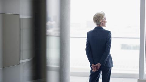 An older businesswoman looks out of an office window