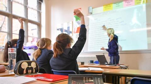 School pupils raise their hands in a lesson