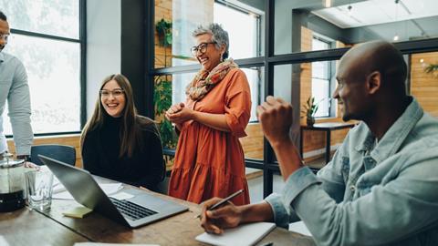 Colleagues laugh together in the office