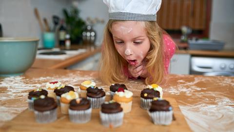 A young girl admires freshly baked cupcakes