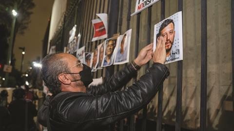A man hangs pictures of five journalists who were murdered in Mexico in 2022