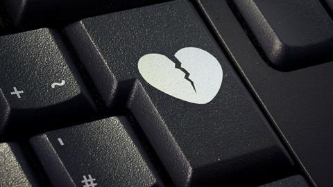 A broken heart graphic on the enter key of a computer keyboard