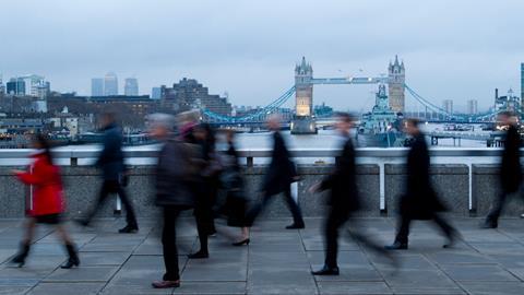 Commuters walk across London Bridge