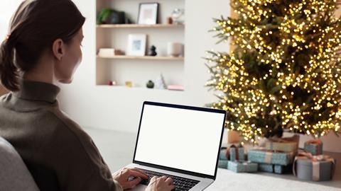 A woman works on her laptop in front of a christmas tree