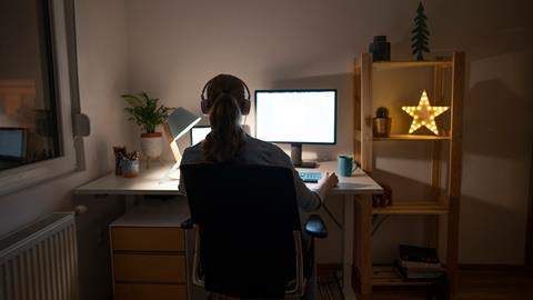 A woman wearing headphones works at her desk late at night