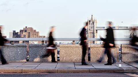 Blurred commuter figures walk with Tower Bridge in the background