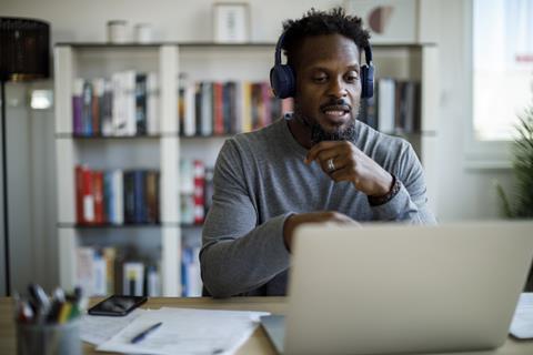 A man wearing headphones talks on a video call at home