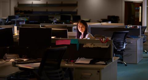 A young woman works late at night in the office