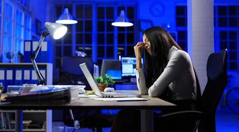 Office worker sat at desk late at night