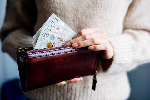 A woman takes £10 notes out of a purse