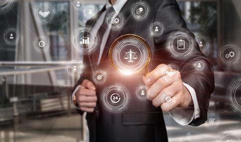 A man in a suit holds up a magnifying glass to a graphic of justice scales