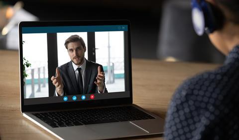 Laptop screen shows businessman talking to woman via Skype