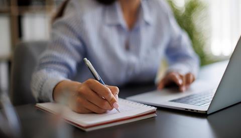 A journalist takes notes during a remote hearing