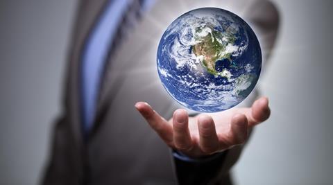 An anonymous business man holds a globe in his hand