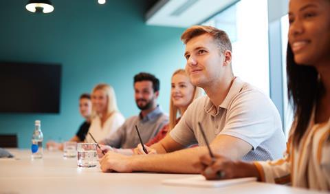 Solicitor apprentices take notes in an office meeting