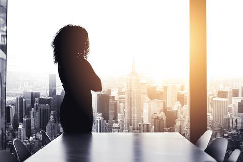 Anonymous business woman stands in an office boardroom and looks out over the city