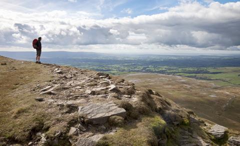 A hiker admires the view from the top of Ingleborough, one of the Three Peaks in the Yorkshire Dales National Park, North Yorkshire