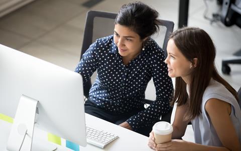 Two female colleagues work together at a computer