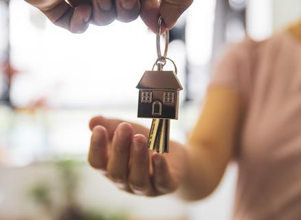 A woman holds out her hand to receive a set of keys to a new house