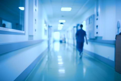 A blurred image of a doctor walking down a hospital corridor