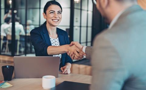 Two people shake hands in a job interview