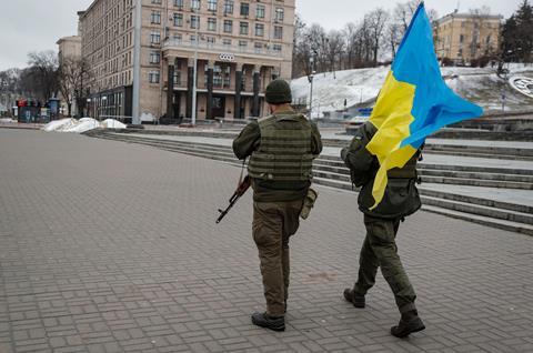 Ukrainian soldiers walk with the Ukrainian national flag in downtown Kyiv