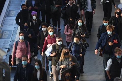 Commuters wearing masks walk through London train station