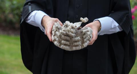 A barrister holds a wig ready to wear