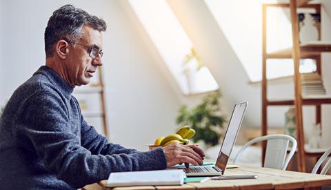 A man types on a laptop at home