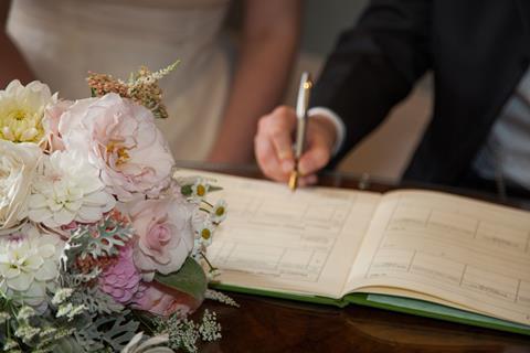 A newly-wedded couple sign their marriage certifcate