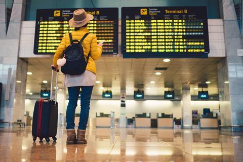 A traveller reads a flight departure board at an airport