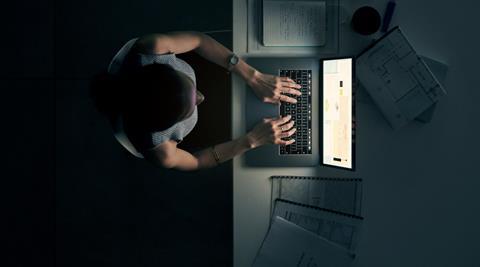 Woman sat at laptop working late at night