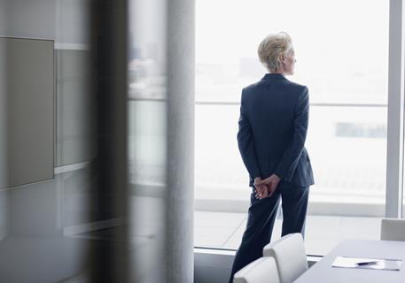 An older businesswoman looks out of an office window