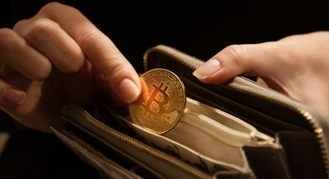 A person takes a Bitcoin 'coin' out of a wallet