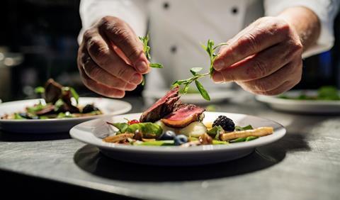 A chef places the finishing touches to a plate of food in a restaurant kitchen