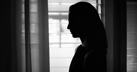 Silhouette of a woman's side profile against light from a window