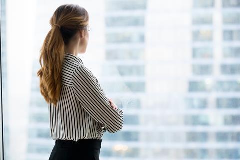 A young woman looks out an office window