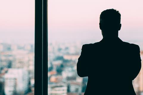 Male office worker looks out of a window